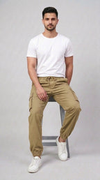 AT7X Khaki Beige 5 pocket loose fit jogger trouser for men, seated view showing loose fit and gathered ankle cuff